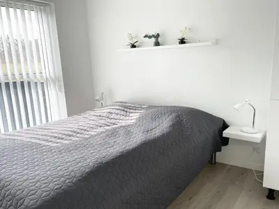 a bedroom with a bed and a table and a window at Holiday Home Dwerg - 1-5km from the sea by Interhome in Løkken