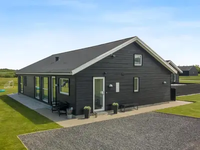 a small black house with a patio and grass at Holiday Home Dwerg - 1-5km from the sea by Interhome in Løkken