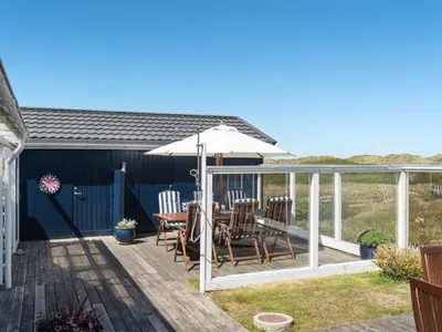 a deck with a table and an umbrella at Holiday Home Ecaterina - 100m from the sea by Interhome in Løkken