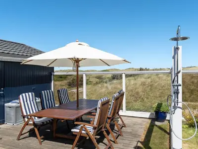 a wooden table with chairs and an umbrella on a deck at Holiday Home Ecaterina - 100m from the sea by Interhome in Løkken