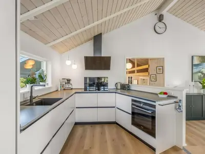 a kitchen with white cabinets and a wooden ceiling at Holiday Home Elna - 400m from the sea by Interhome in Løkken