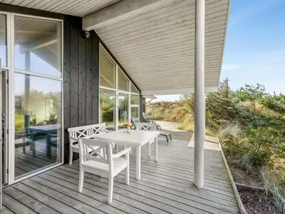 a porch with a white table and chairs on it at Holiday Home Elna - 400m from the sea by Interhome in Løkken