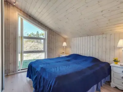 a bedroom with a blue bed and a window at Holiday Home Herwarth - 3-3km from the sea by Interhome in Blokhus