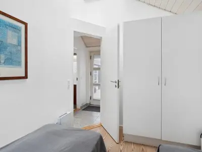 a bedroom with white cabinets and a bed in it at Holiday Home Frethi - 350m from the sea by Interhome in Blokhus