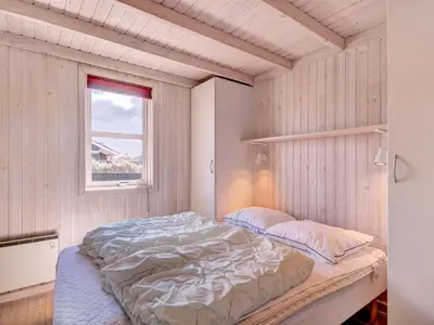 a bedroom with a bed in a wooden wall at Holiday Home Nedelko - 250m from the sea by Interhome in Blokhus