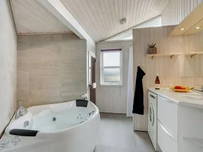 a large white tub in a bathroom with a sink at Holiday Home Nedelko - 250m from the sea by Interhome in Blokhus