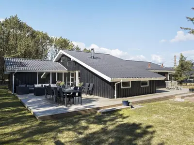 a black house with a table and chairs on a deck at Holiday Home Yessica - 300m from the sea by Interhome in Løkken