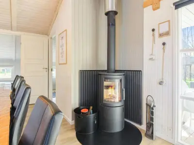 a wood stove in a room with a table and chairs at Holiday Home Yessica - 300m from the sea by Interhome in Løkken