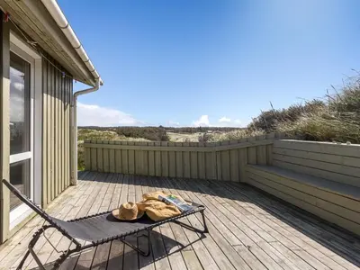 a deck with a chair and a table on it at Holiday Home Kalervo - 100m from the sea by Interhome in Pandrup