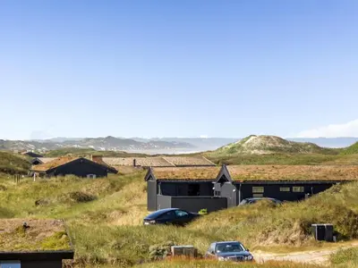 two cars parked in a field next to a building at Holiday Home Kalervo - 100m from the sea by Interhome in Pandrup
