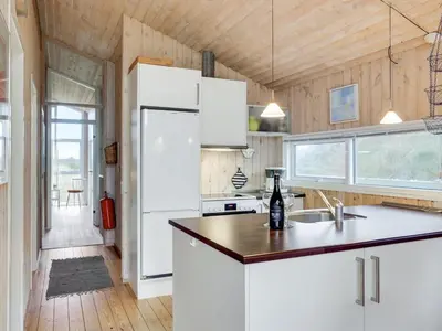a kitchen with white cabinets and a white refrigerator at Holiday Home Kalervo - 100m from the sea by Interhome in Pandrup