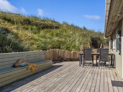 a wooden deck with a table and chairs and a table and a table and chairs at Holiday Home Kalervo - 100m from the sea by Interhome in Pandrup