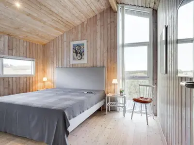 a bedroom with a large bed and two windows at Holiday Home Kalervo - 100m from the sea by Interhome in Pandrup