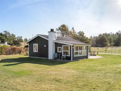 a small black house on a grass field at Holiday Home Ingebritt - 1-5km from the sea by Interhome in Blokhus