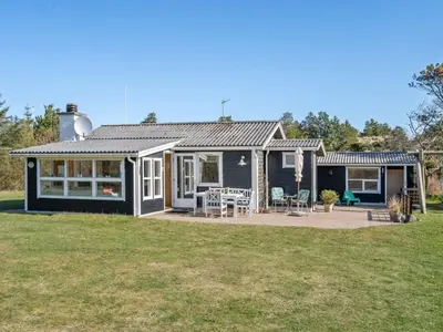a black house with a patio in the yard at Holiday Home Ingebritt - 1-5km from the sea by Interhome in Blokhus