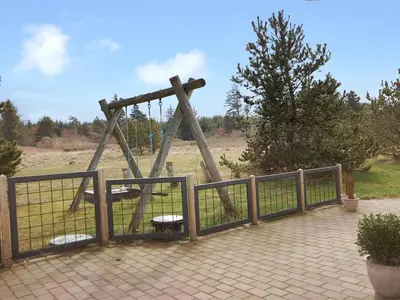 a playground with a swing in a park at Holiday Home Ingebritt - 1-5km from the sea by Interhome in Blokhus