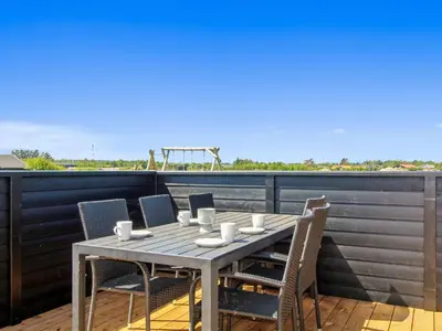a wooden table and chairs on a balcony at Holiday Home Elenore - 900m from the sea by Interhome in Løkken