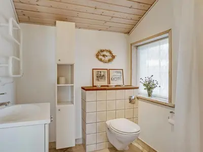 a bathroom with a toilet and a sink and a window at Holiday Home Felizia - 2-5km from the sea by Interhome in Blokhus