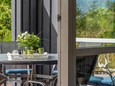 a table on the balcony with flowers on it at Holiday Home Felizia - 2-5km from the sea by Interhome in Blokhus