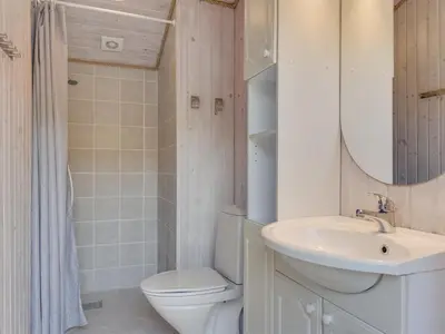 a bathroom with a toilet and a sink and a mirror at Holiday Home Ninna - 1km from the sea by Interhome in Blokhus