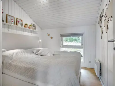 a white bedroom with a large bed in it at Holiday Home Elayne - 3km from the sea by Interhome in Blokhus