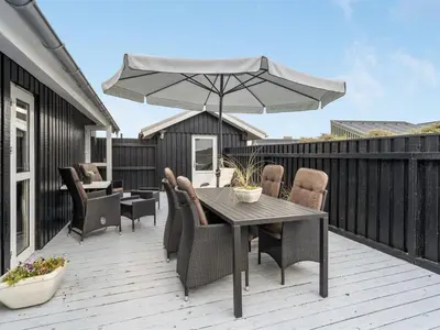 a patio with a table and chairs and an umbrella at Holiday Home Arwen - 200m from the sea by Interhome in Blokhus