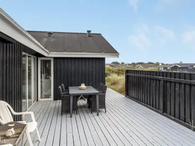 a wooden deck with a table and chairs on it at Holiday Home Arwen - 200m from the sea by Interhome in Blokhus
