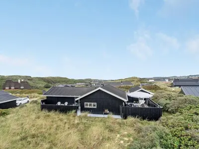 a black house sitting on top of a hill at Holiday Home Arwen - 200m from the sea by Interhome in Blokhus