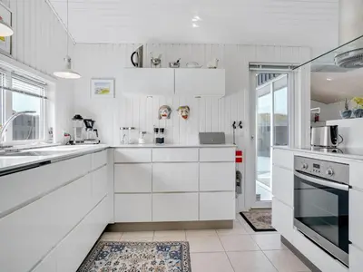 a white kitchen with white cabinets and appliances at Holiday Home Arwen - 200m from the sea by Interhome in Blokhus