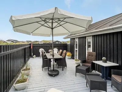 a patio with an umbrella and a table and chairs at Holiday Home Arwen - 200m from the sea by Interhome in Blokhus