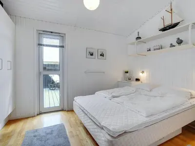 a white bedroom with a large bed and a window at Holiday Home Arwen - 200m from the sea by Interhome in Blokhus