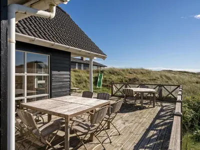 a wooden deck with a table and chairs on it at Holiday Home Maren - 150m from the sea by Interhome in Blokhus