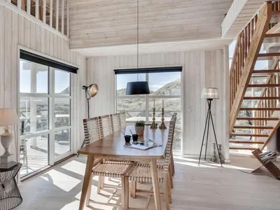 a dining room with a wooden table and chairs at Holiday Home Maren - 150m from the sea by Interhome in Blokhus