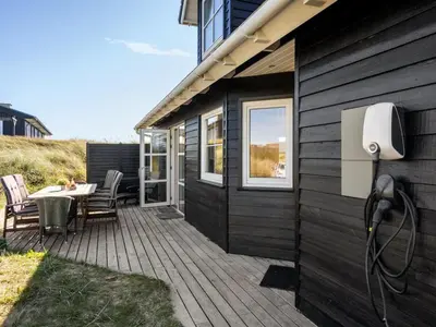 a wooden deck with a table and chairs on a house at Holiday Home Maren - 150m from the sea by Interhome in Blokhus