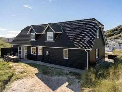 a house with a black roof on a beach at Holiday Home Maren - 150m from the sea by Interhome in Blokhus