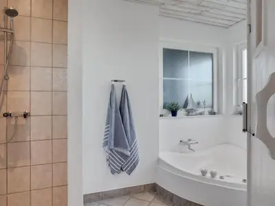 a bathroom with a bath tub and a sink at Holiday Home Maren - 150m from the sea by Interhome in Blokhus