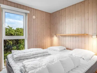 a large white bed in a room with a window at Holiday Home Skamhals - 700m from the sea by Interhome in Blokhus
