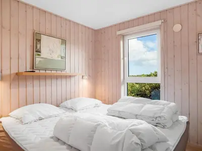 a bedroom with a large white bed with a window at Holiday Home Skamhals - 700m from the sea by Interhome in Blokhus