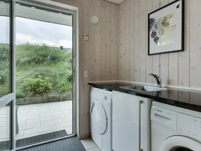a laundry room with a sink and a washing machine at Holiday Home Skamhals - 700m from the sea by Interhome in Blokhus