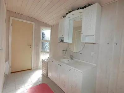 a white bathroom with a sink and a mirror at Holiday Home Tomke - 1-7km from the sea by Interhome in Blokhus