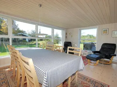 a dining room with a table and chairs and windows at Holiday Home Tomke - 1-7km from the sea by Interhome in Blokhus
