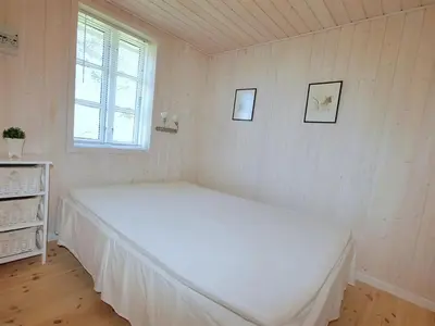 a bedroom with a white bed with two pictures on the wall at Holiday Home Tomke - 1-7km from the sea by Interhome in Blokhus
