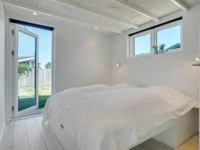 a white bedroom with a large bed and windows at Holiday Home Erk - 700m from the sea by Interhome in Blokhus