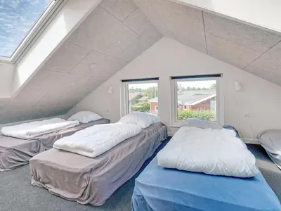 a attic room with three beds and a window at Holiday Home Erk - 700m from the sea by Interhome in Blokhus