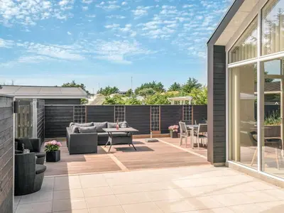 a patio with a couch and a table and chairs at Holiday Home Erk - 700m from the sea by Interhome in Blokhus