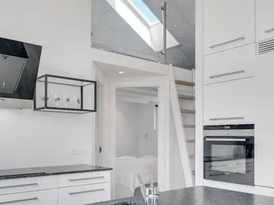 a kitchen with white cabinets and a spiral staircase at Holiday Home Erk - 700m from the sea by Interhome in Blokhus