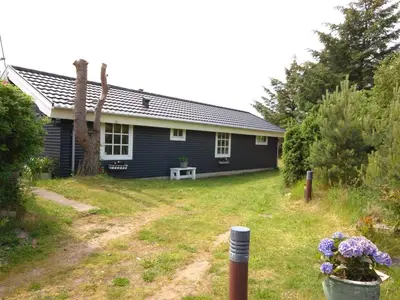 a blue house with a porch and flowers in the yard at Holiday Home Tajo - 1km from the sea by Interhome in Blokhus