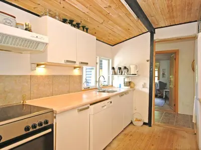 a kitchen with white cabinets and a wooden ceiling at Holiday Home Tajo - 1km from the sea by Interhome in Blokhus
