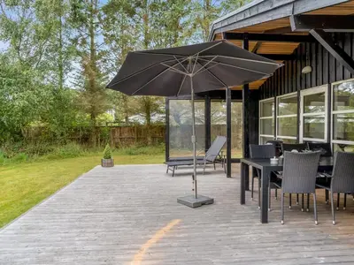 a patio with a table and chairs and an umbrella at Holiday Home Bernadeta - 1-2km from the sea by Interhome in Blokhus