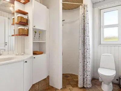 a white bathroom with a toilet and a shower at Holiday Home Alrune - 800m from the sea by Interhome in Blokhus